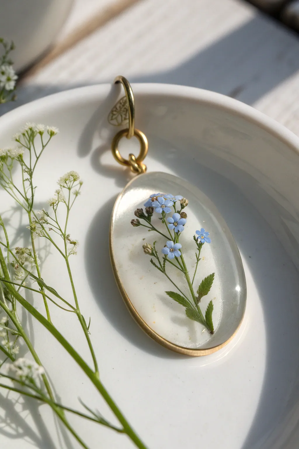 Translucent polymer clay locket with tiny dried flowers, minimal and softly sunlit