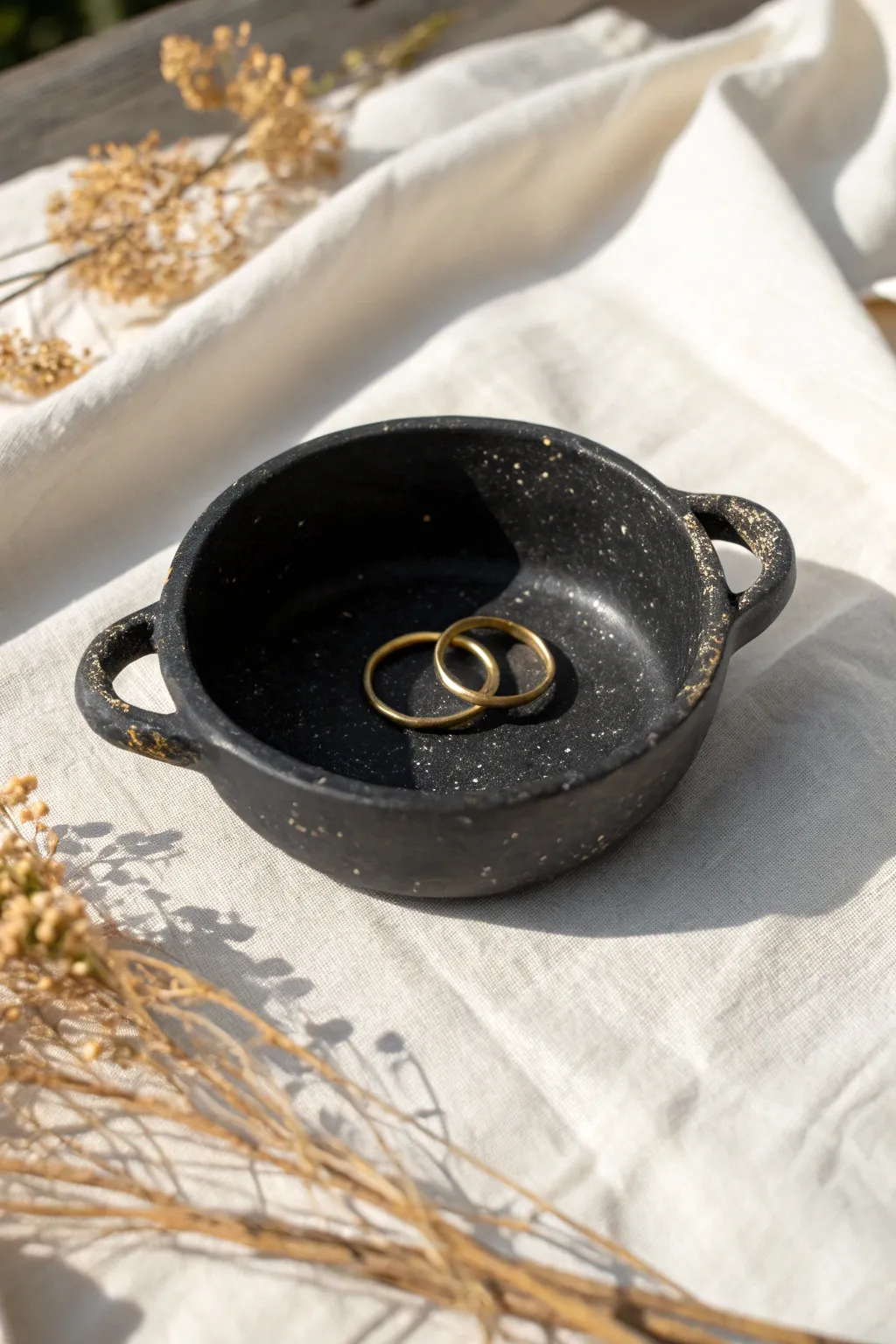 Little black cauldron ring dish with speckled glaze, minimalist boho styling, softly lit.
