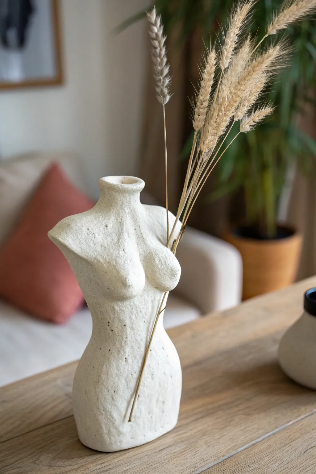 Boho female torso bud vase in creamy clay, styled minimal with dried stems and bold contrast.