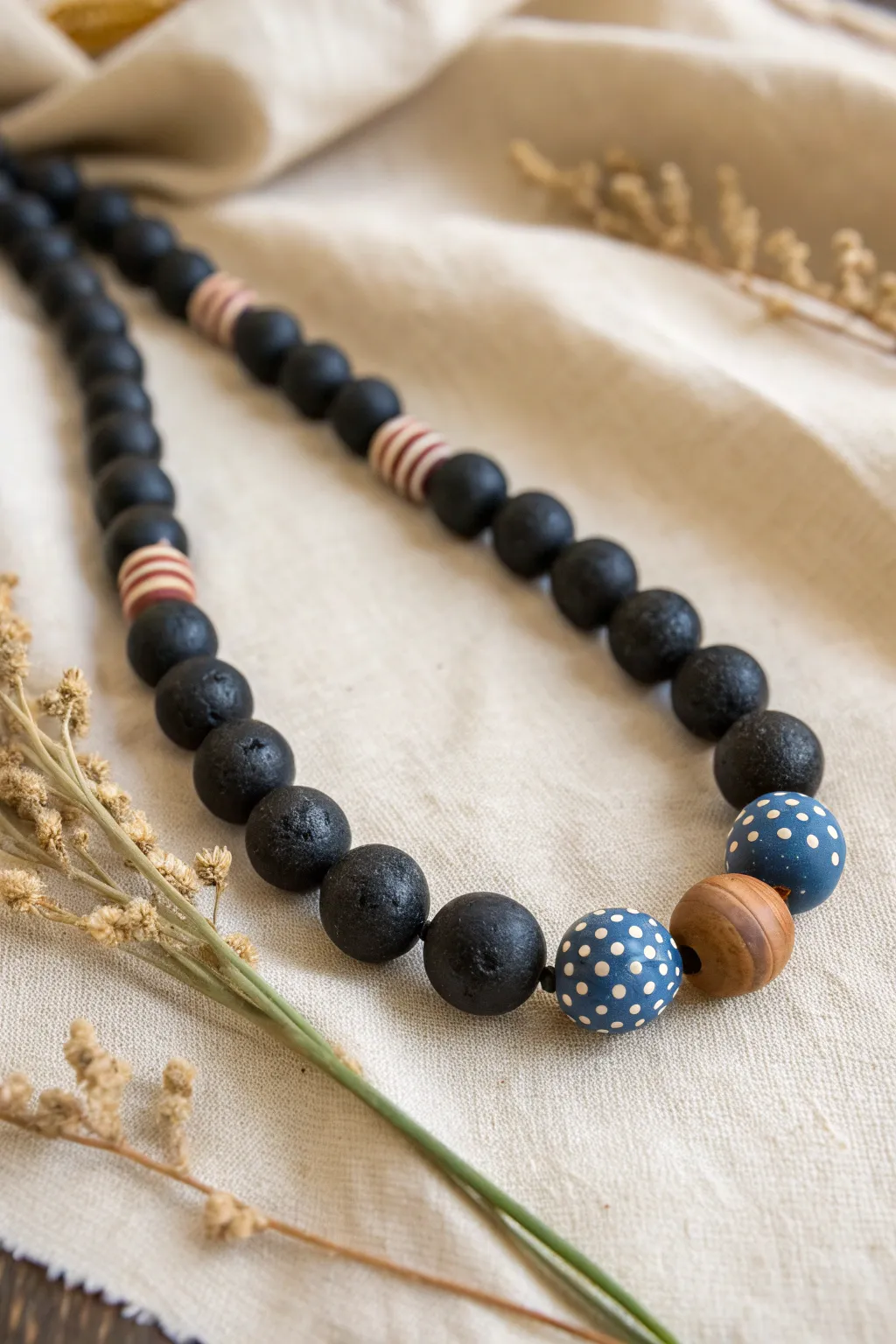 Chunky black clay beads with tiny white inlays and one bold color accent, minimalist and handmade.