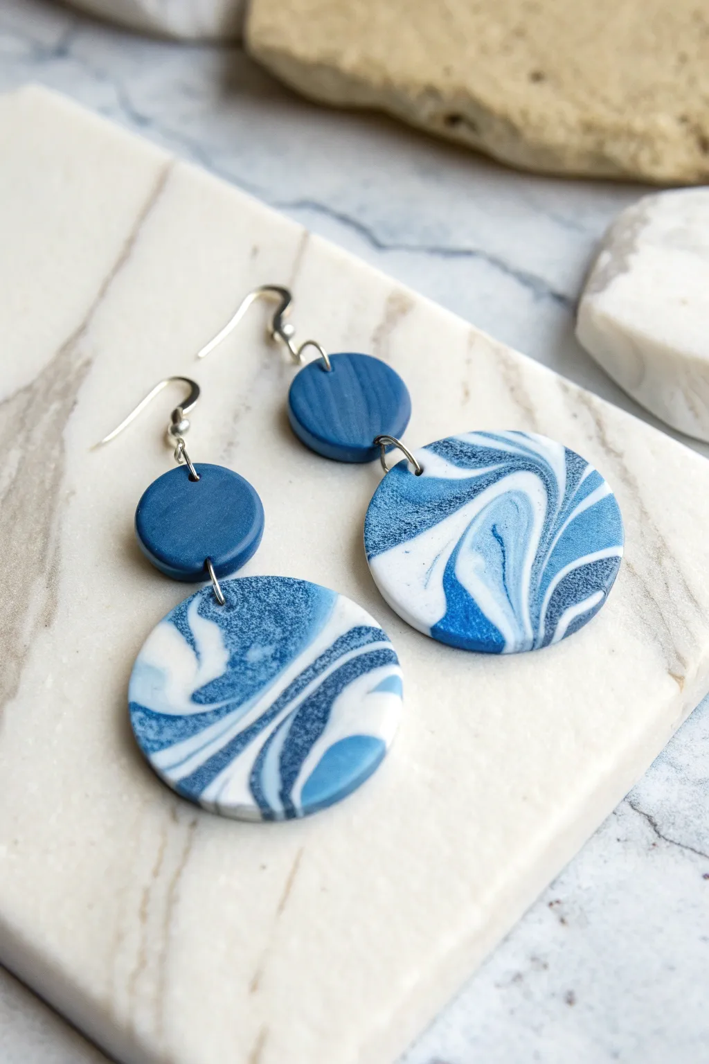 Blue marble swirl dangle earrings in navy and sky blue with white veining on pale stone.