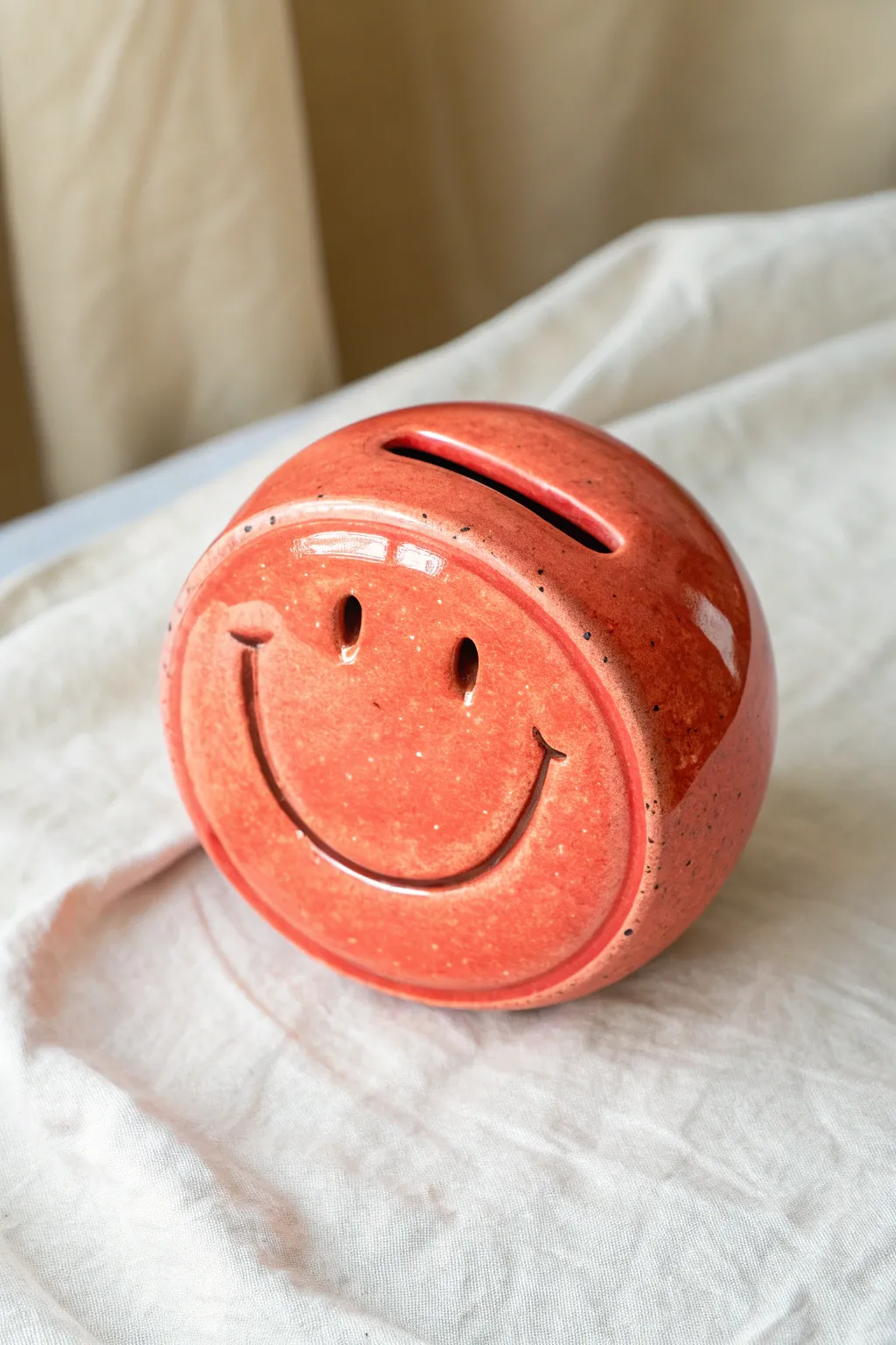 Bold smiley face clay disk bank in vibrant glaze, minimalist boho style with high contrast.