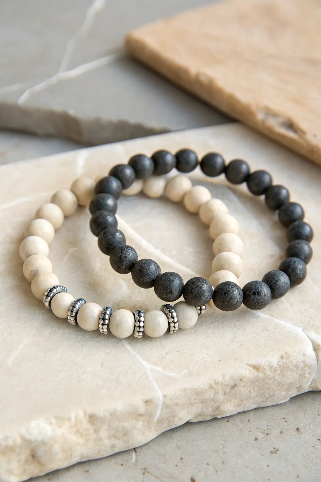 Monochrome couple bracelets in cream and charcoal with matching shiny spacers for a sleek pair.