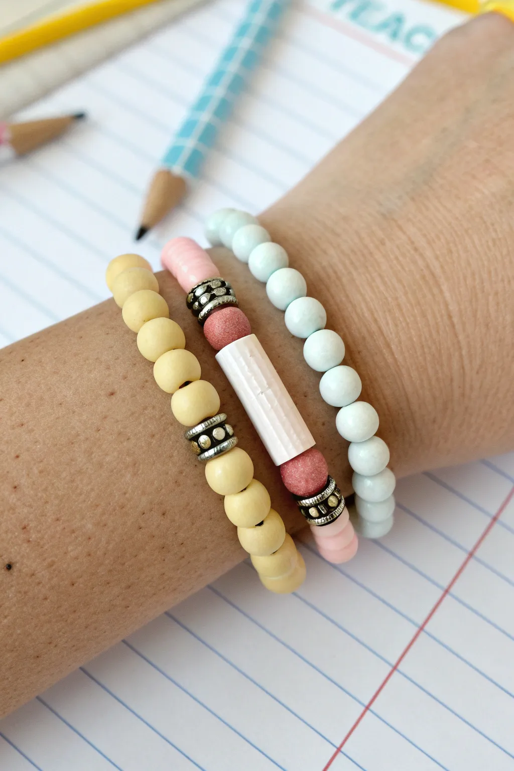 Three teacher clay bead bracelets in a gift ready stack: pencil, lined paper, and notebook charm