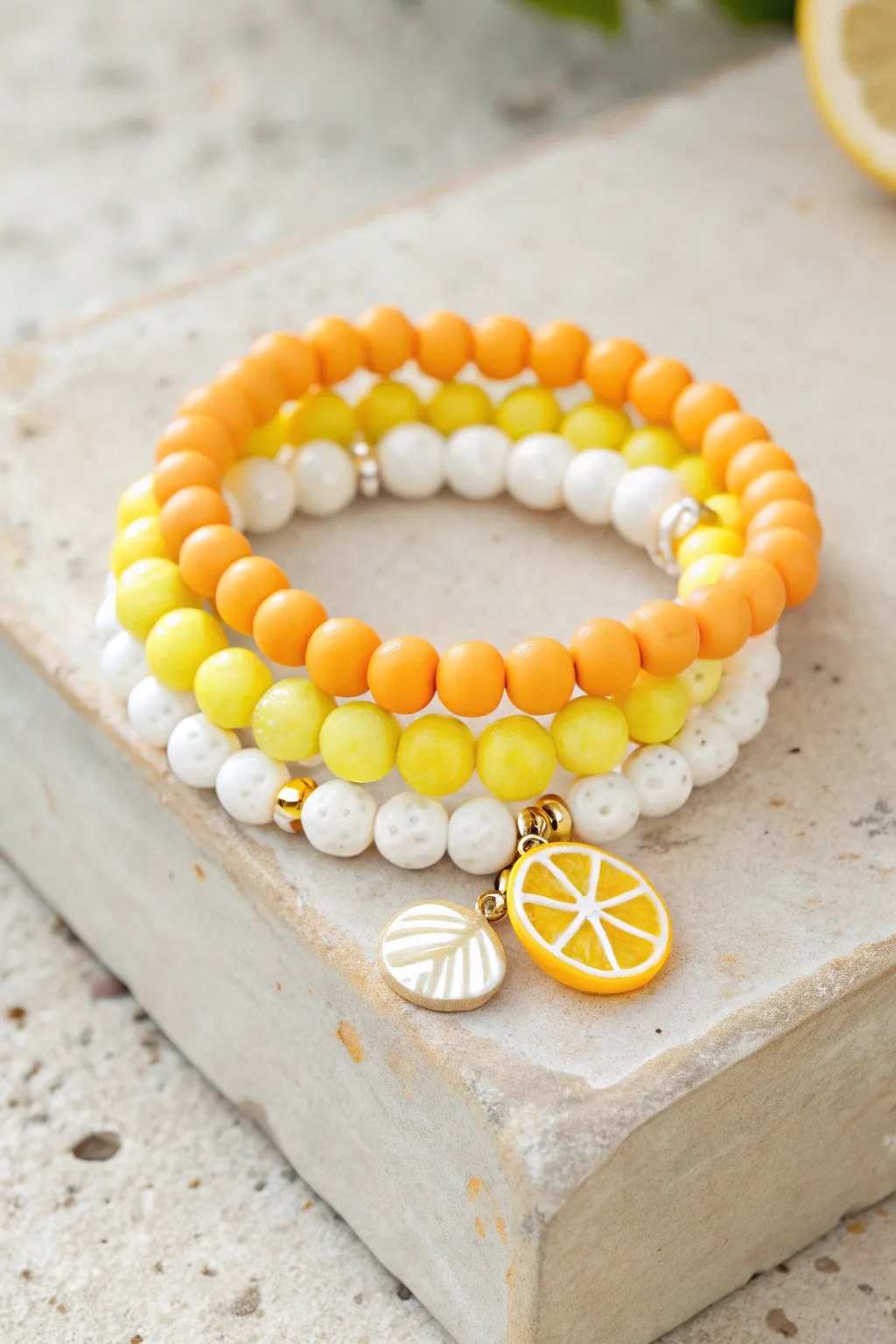 Citrus slice clay bead bracelet stack in lemon, orange, and white for a bright summer look