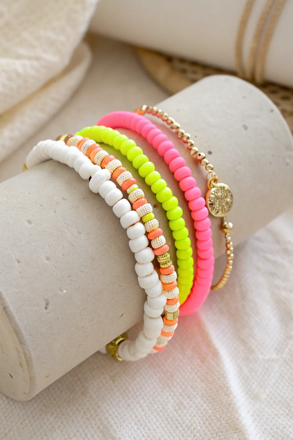 Neon and white heishi clay bead bracelet stack with gold spacers for a crisp preppy pop.