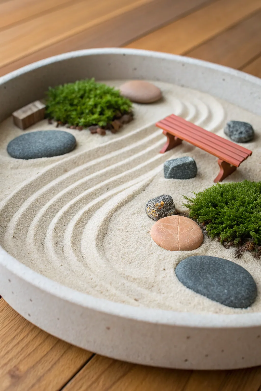 Stone-texture zen garden in a dish: clay pebbles, tiny bench, moss, and a winding path.