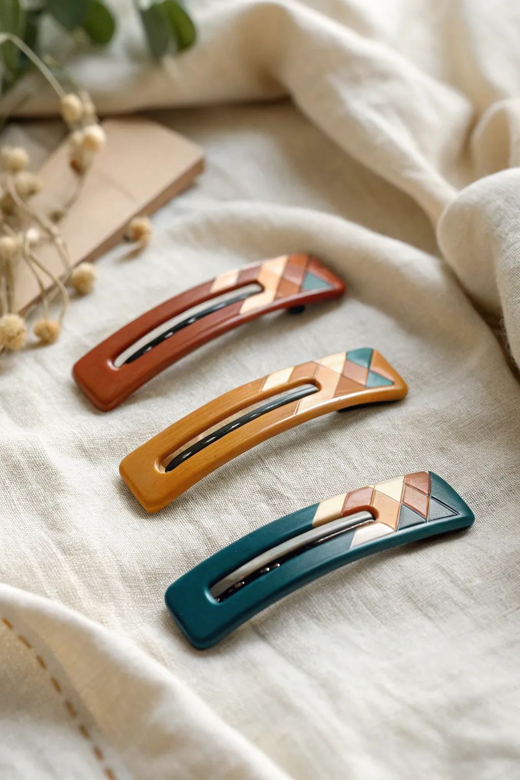 Handmade clay hair clips with simple patterns and bold color blocks, styled on soft linen.