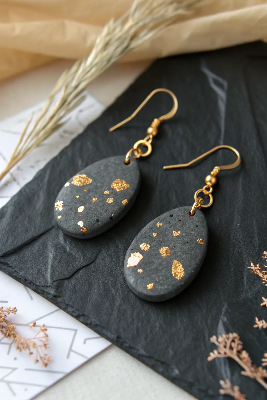 Dark clay dangles with scattered gold foil accents for a bold, minimalist handmade look.