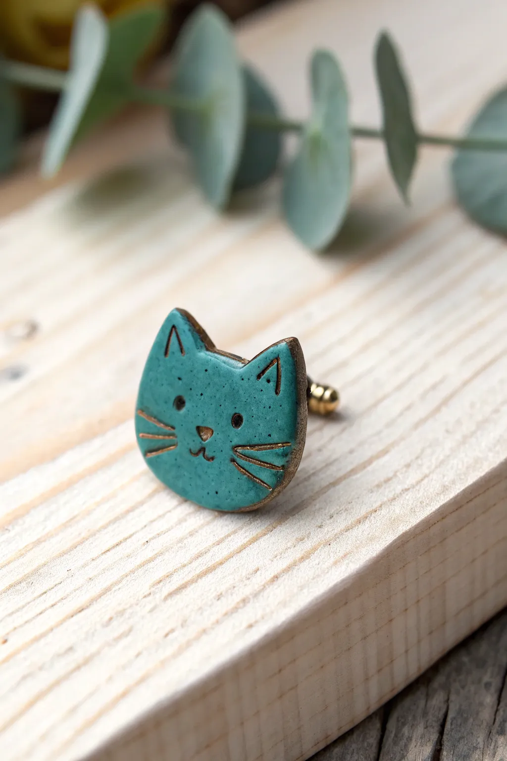 Minimal cat face clay pin in bold teal, handcrafted charm with clean Scandinavian simplicity