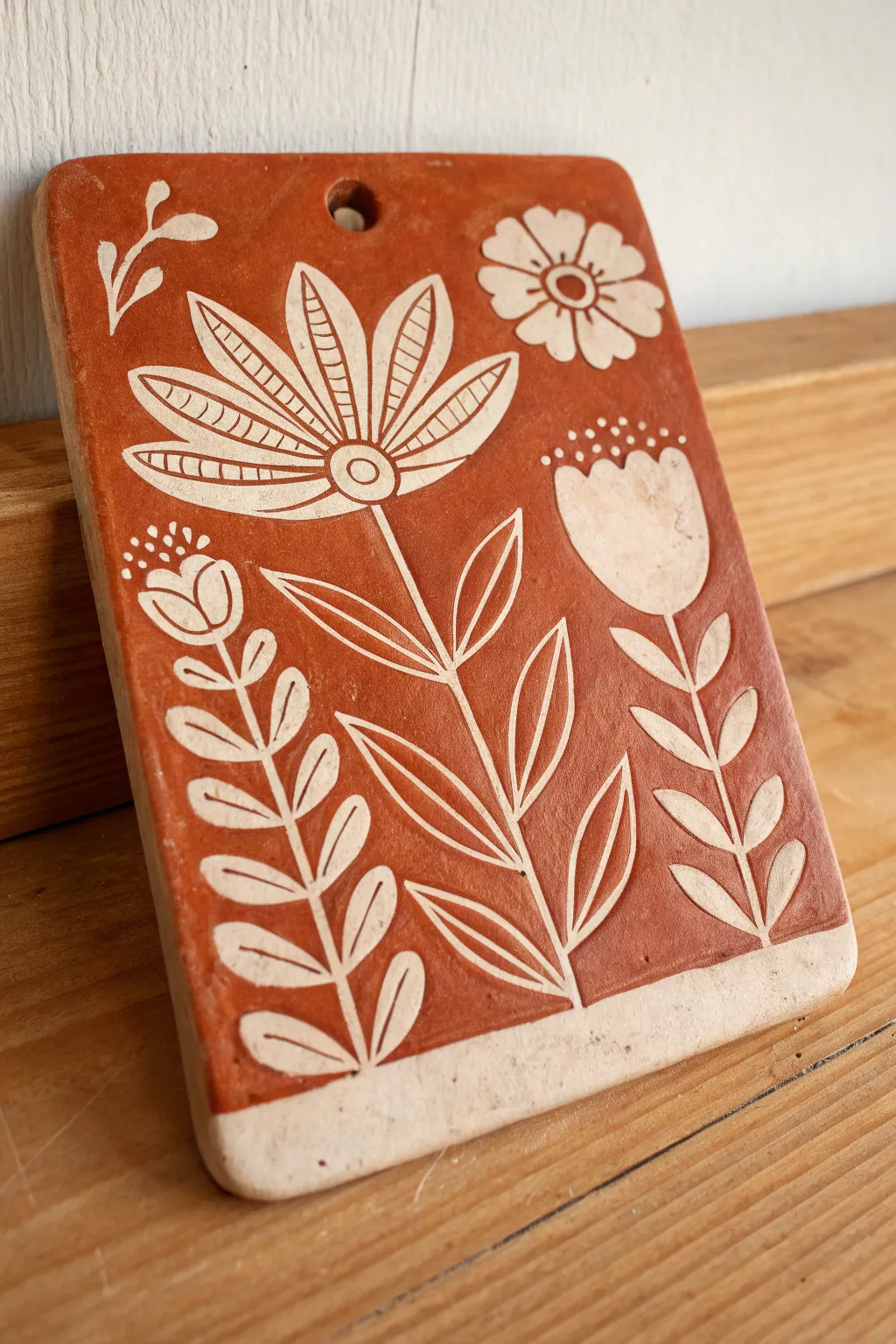 Minimalist sgraffito slab plaque with bold carved florals and a hanging hole, earthy and modern