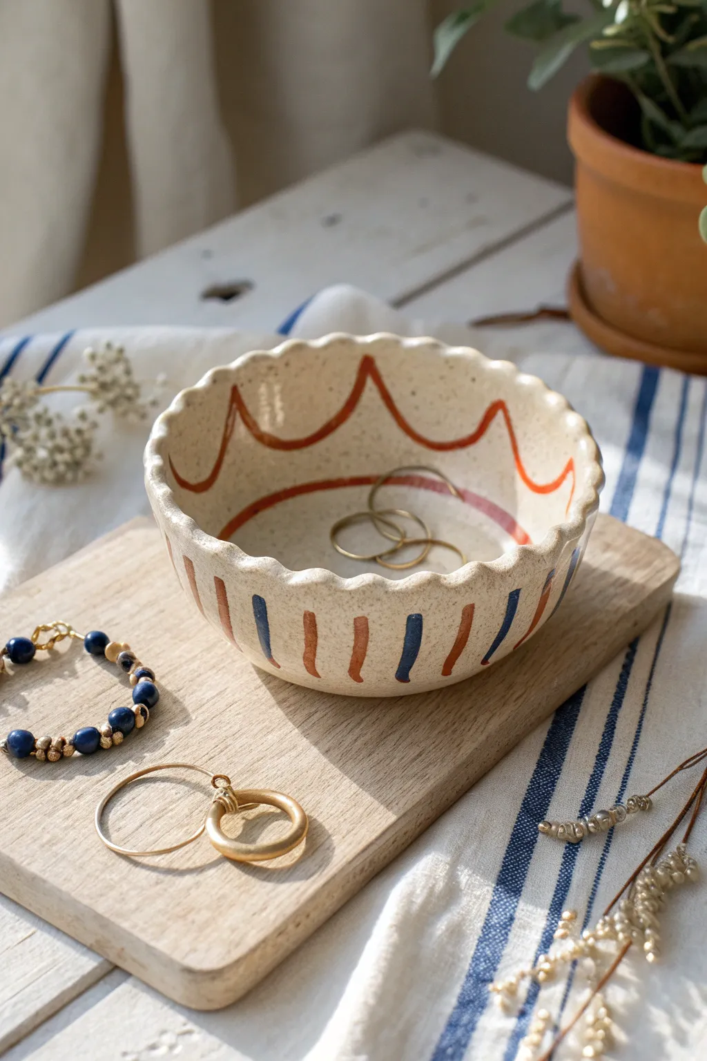 Wavy rim clay jewelry bowl with bold stripes, softly styled on a minimal Scandinavian vanity.