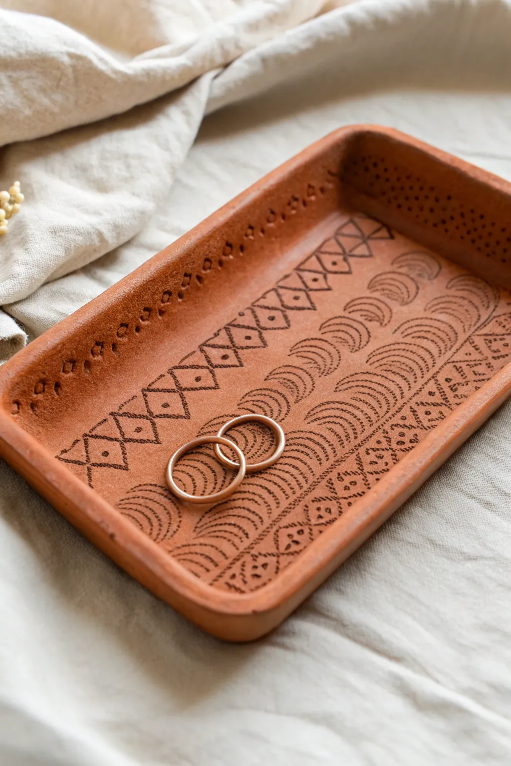 Stamped clay tray with a rich contrast wash, styled on linen with earrings for easy boho charm.