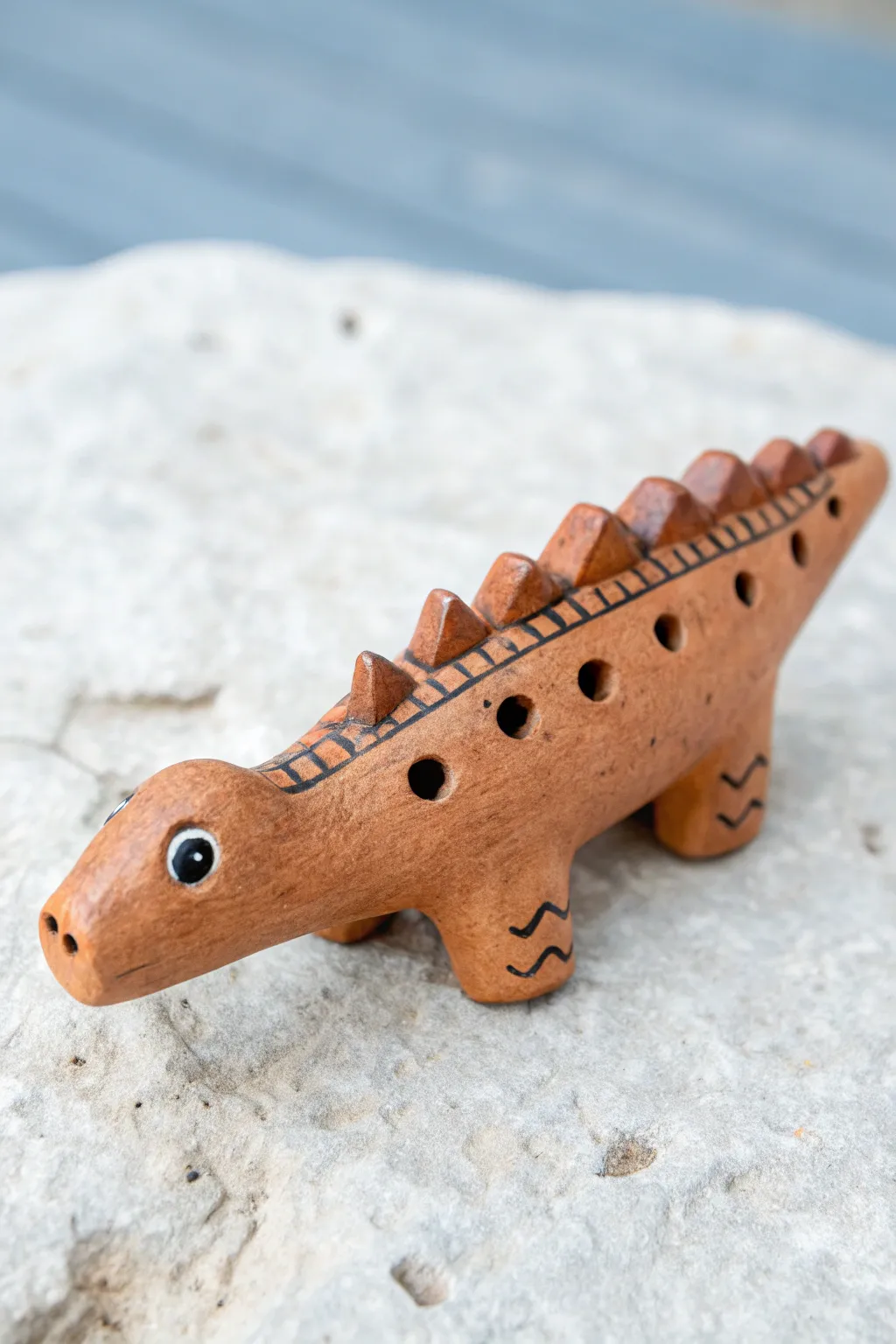 Easy dinosaur clay whistle with simple spike ridge, playful dot eye, and side mouthpiece