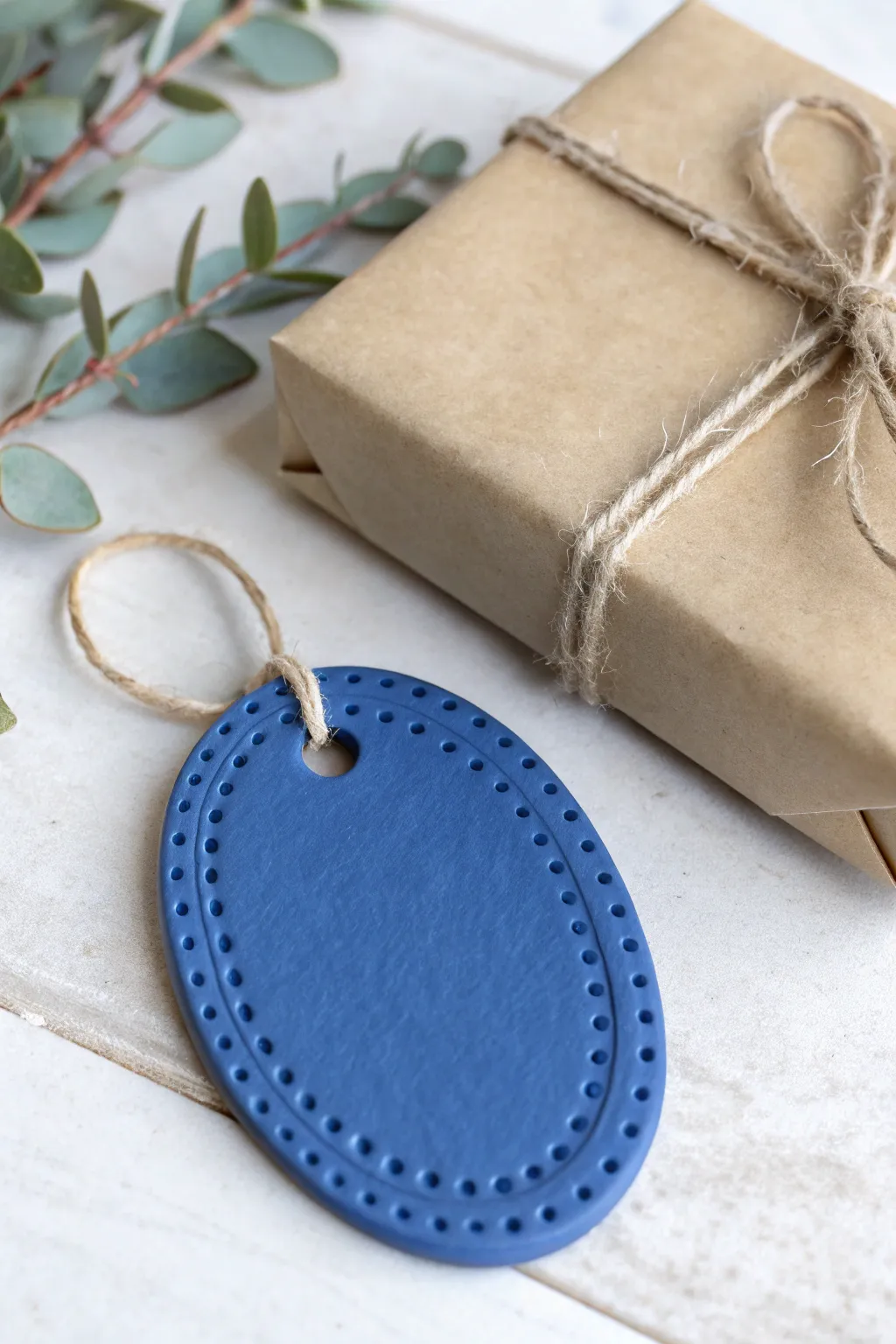 Bold cobalt cold porcelain gift tag with hand stamped texture tied to a minimalist wrapped present