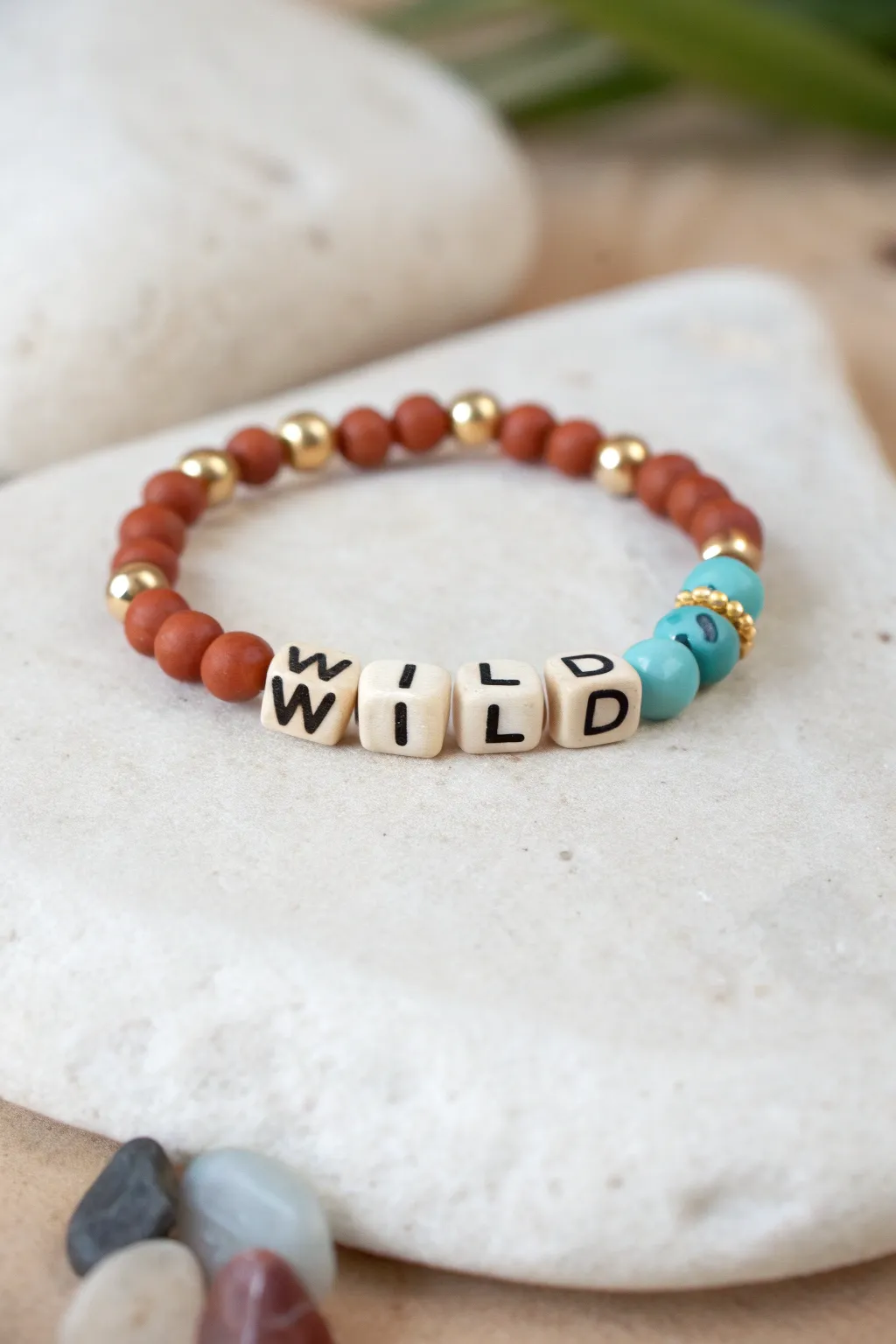 Cowgirl clay bead bracelet with WILD letters, warm earth tones, and a turquoise pop