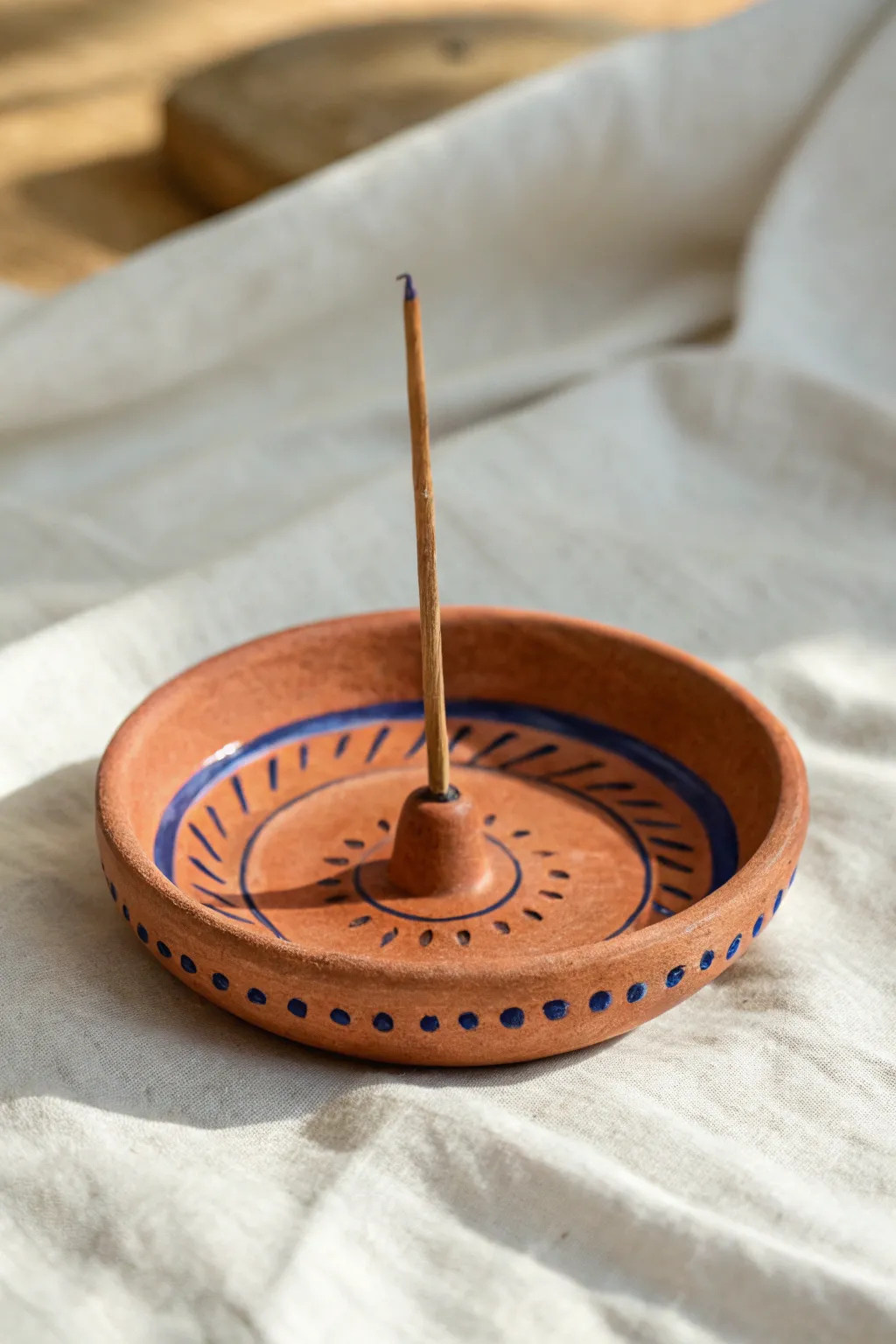 Textured clay incense holder with carved dots and bold glaze, styled on a calm neutral backdrop.