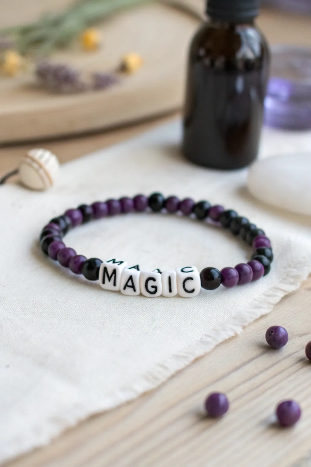 Purple, black, and white heishi bracelet with MAGIC letter beads, styled with a minimalist potion vibe.