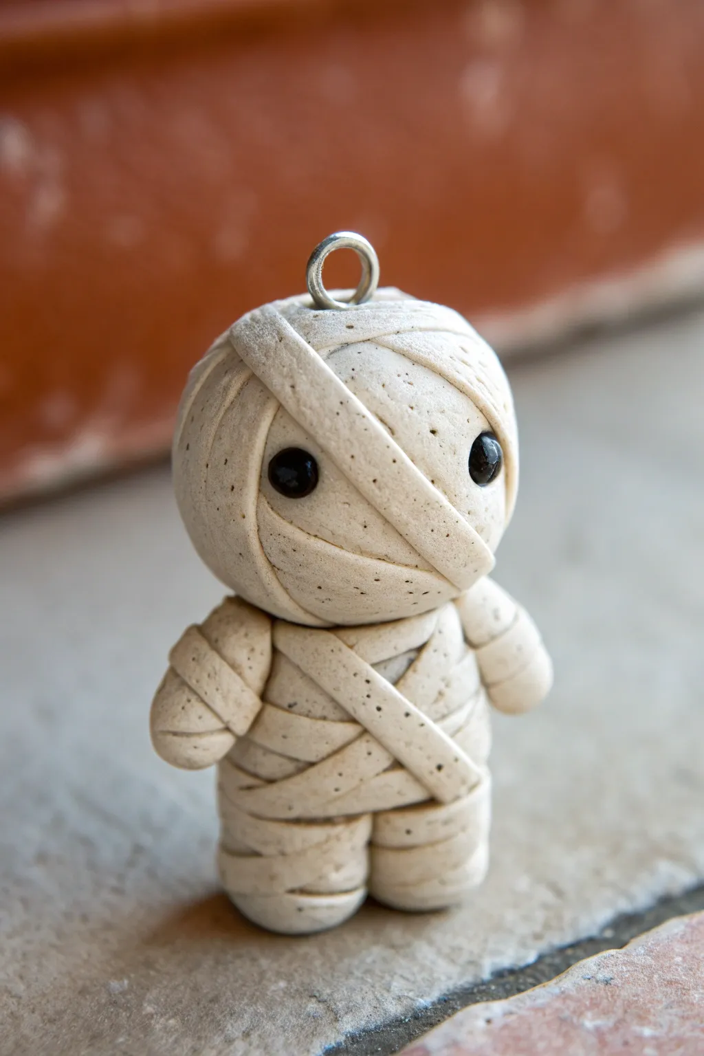 Adorable mini mummy charm with raised wraps and dot eyes, an easy Halloween clay idea to try