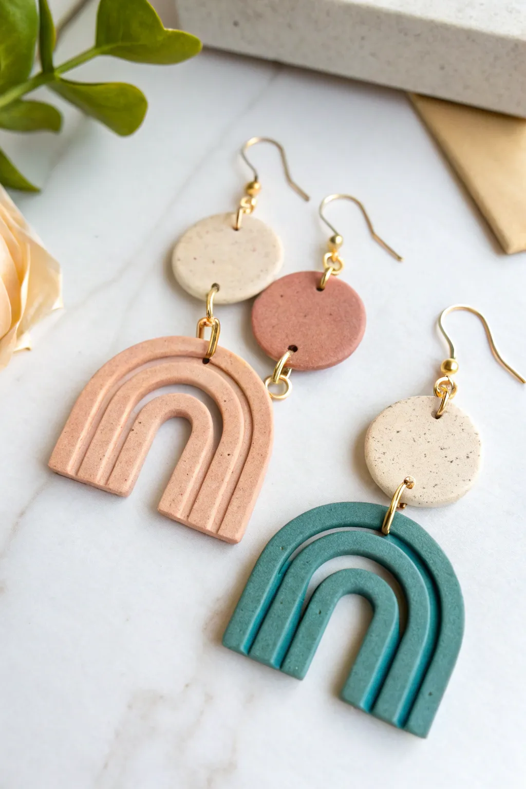 Minimal geometric air dry clay dangle earrings in muted tones, clean flat lay with bold contrast