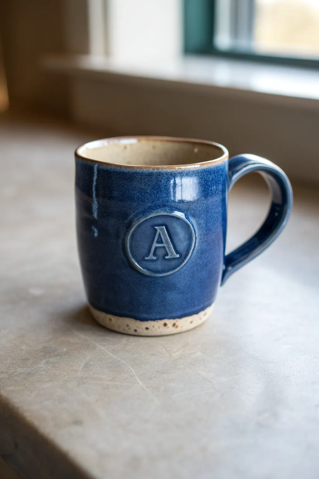 Glossy handmade mug with a raised initial medallion, simple, bold, and totally yours.