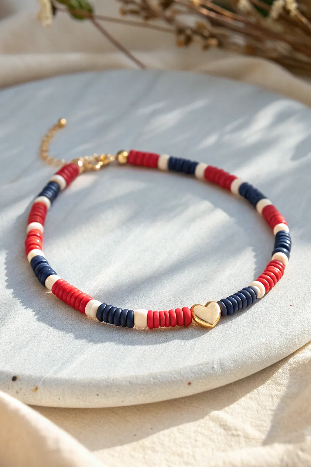 Preppy heishi clay bead bracelet with an off-center heart and gold spacers, minimal and chic.