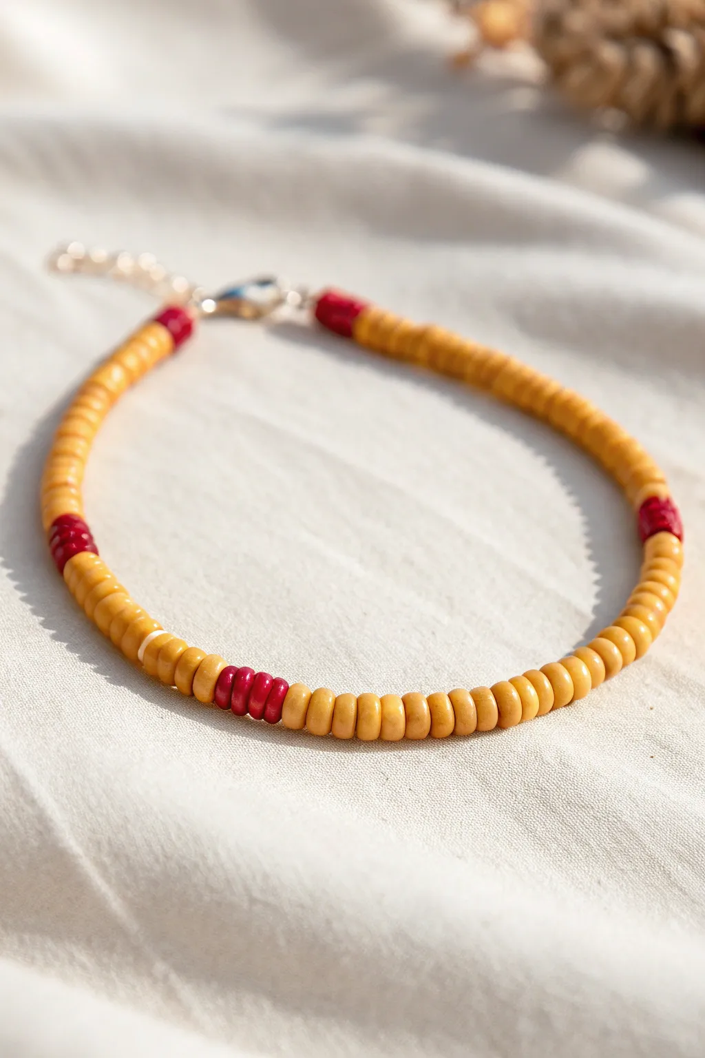 Minimalist yellow heishi bracelet with one red stitch stripe for a subtle softball-inspired look