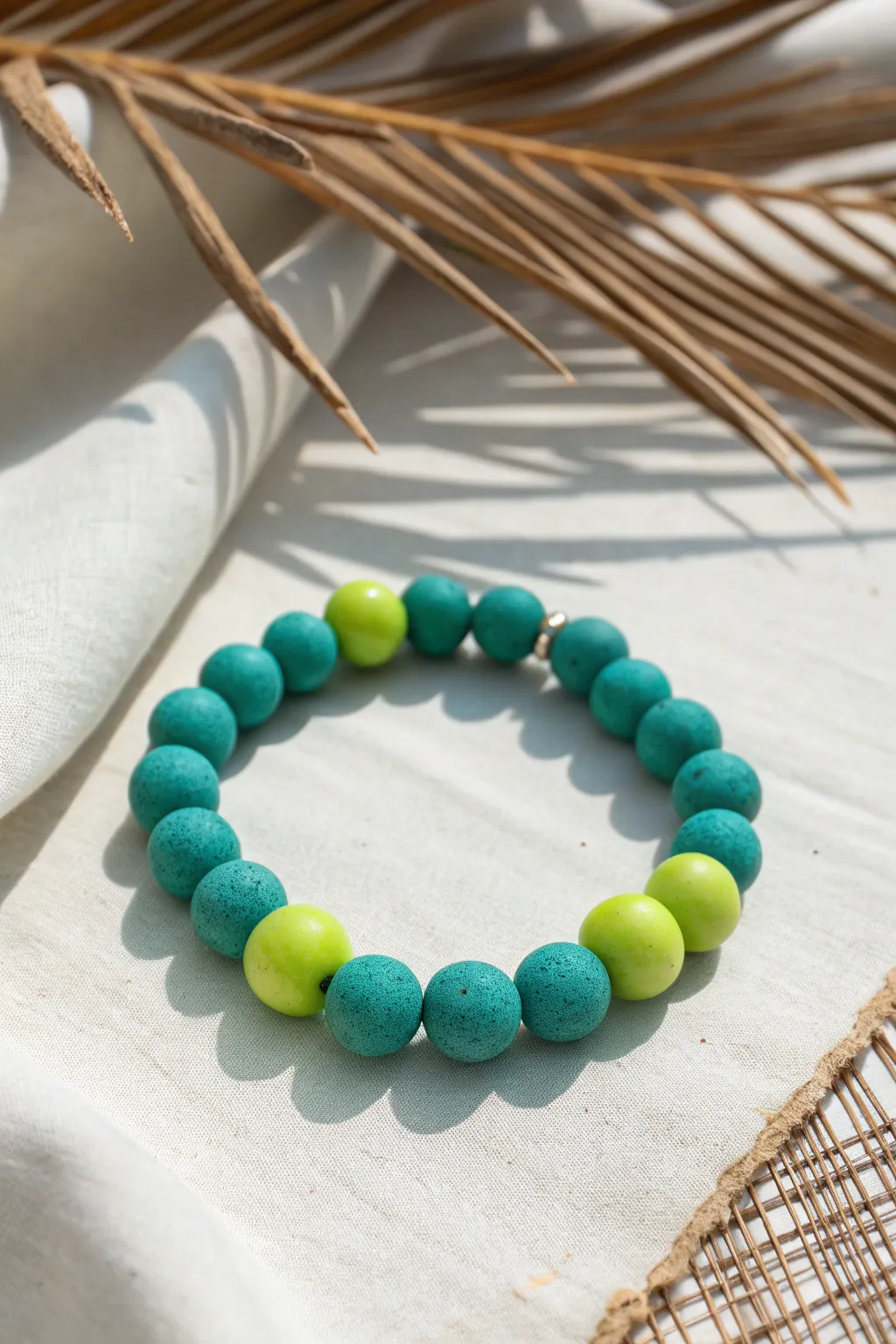 Teal clay bead bracelet with zesty lime accents, minimalist flat-lay for bright boho vibes.