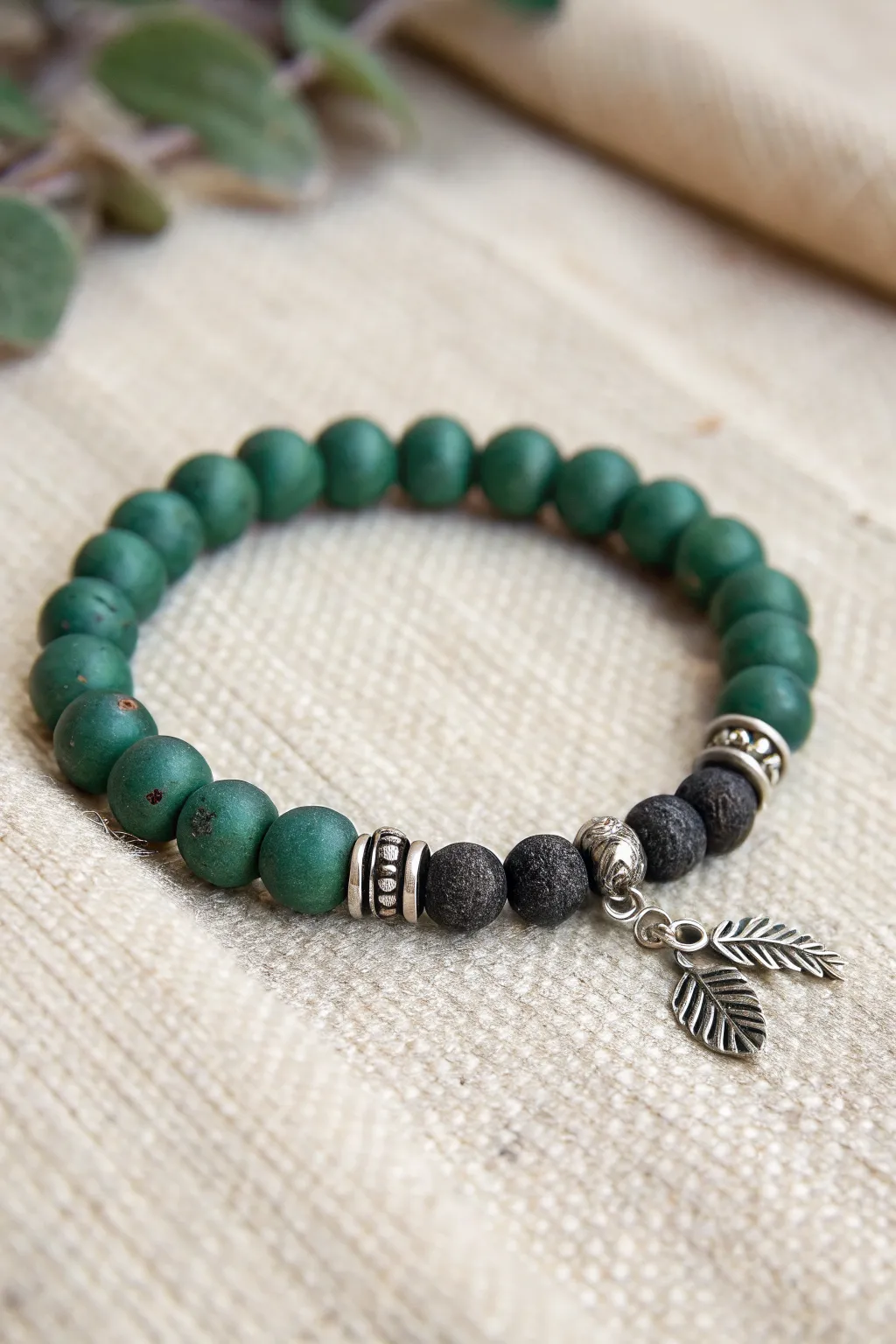 Dark glam broomstick charm bracelet in green, black, and metallic beads, bold yet minimalist.