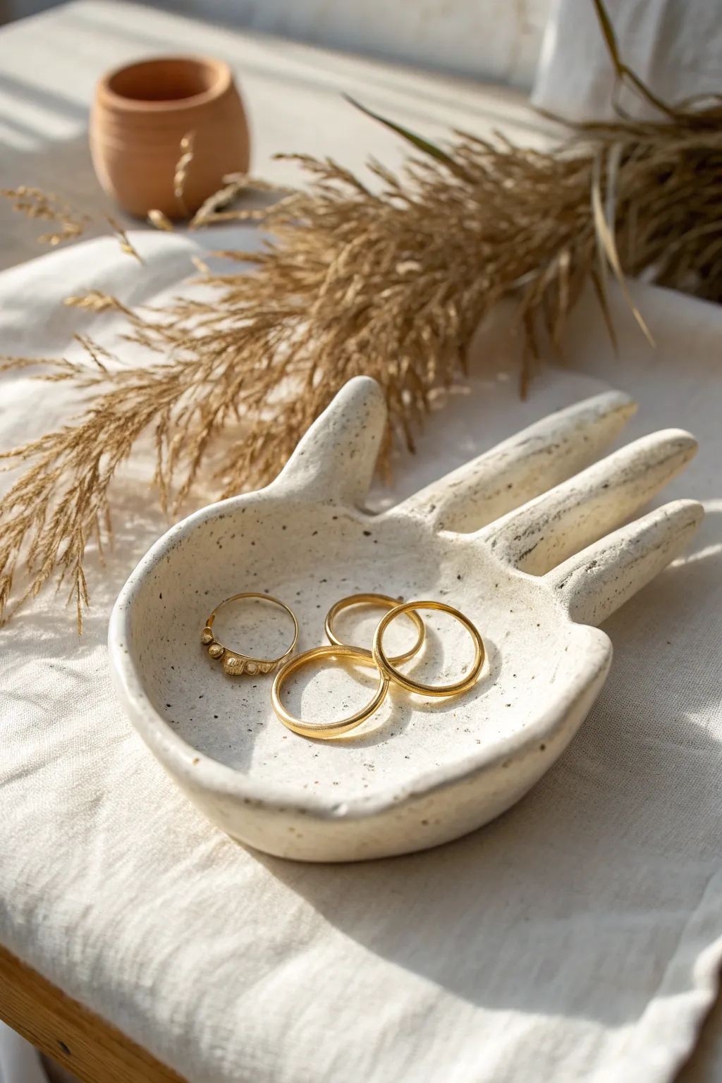 Minimal hand-shaped air dry clay dish holding a few rings, soft light and neutral tones