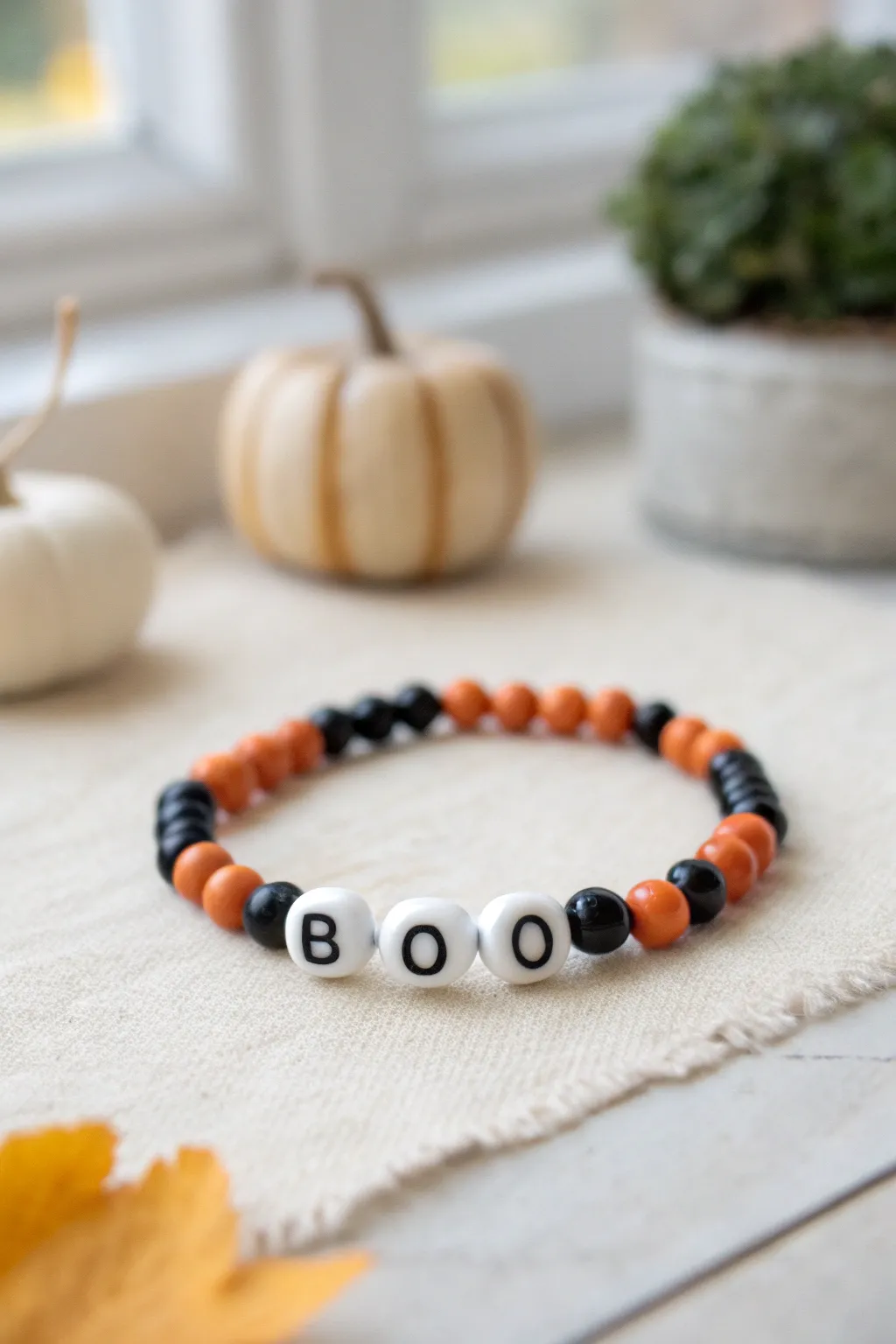 Playful orange and black clay bead bracelet with BOO accents, styled in cozy autumn minimalism