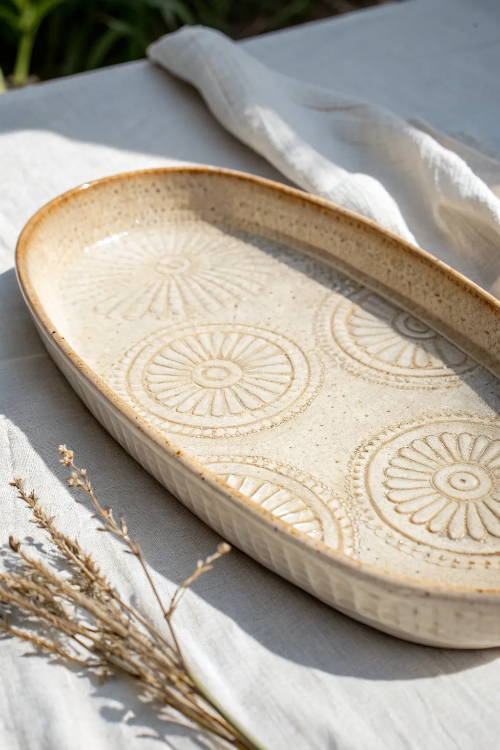 Glossy pooling glaze highlights stamped texture on a minimalist oval ceramic tray.