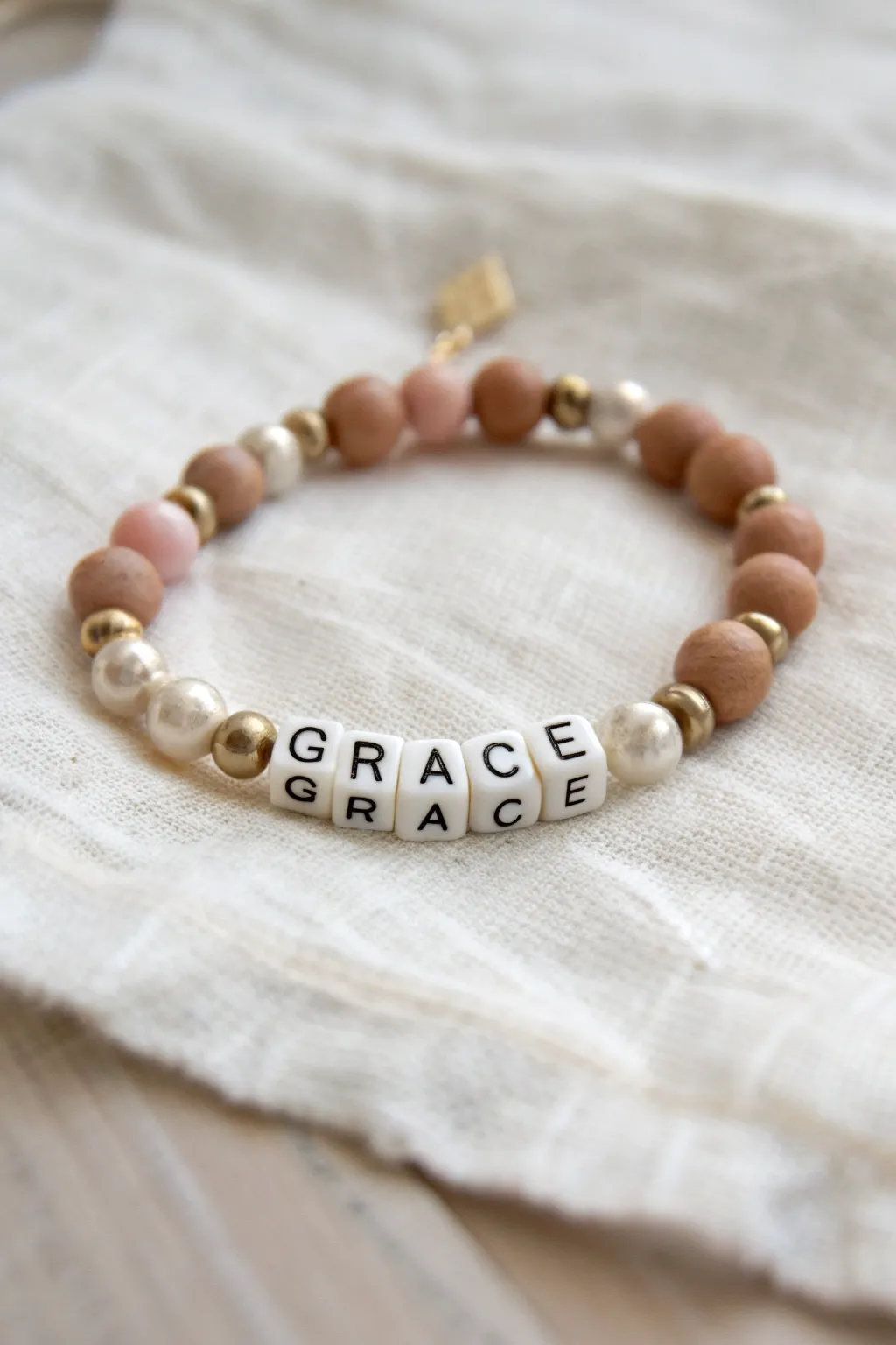 Minimal clay heishi bracelet with pearl accents and GRACE letter beads, soft boho Scandinavian vibe.