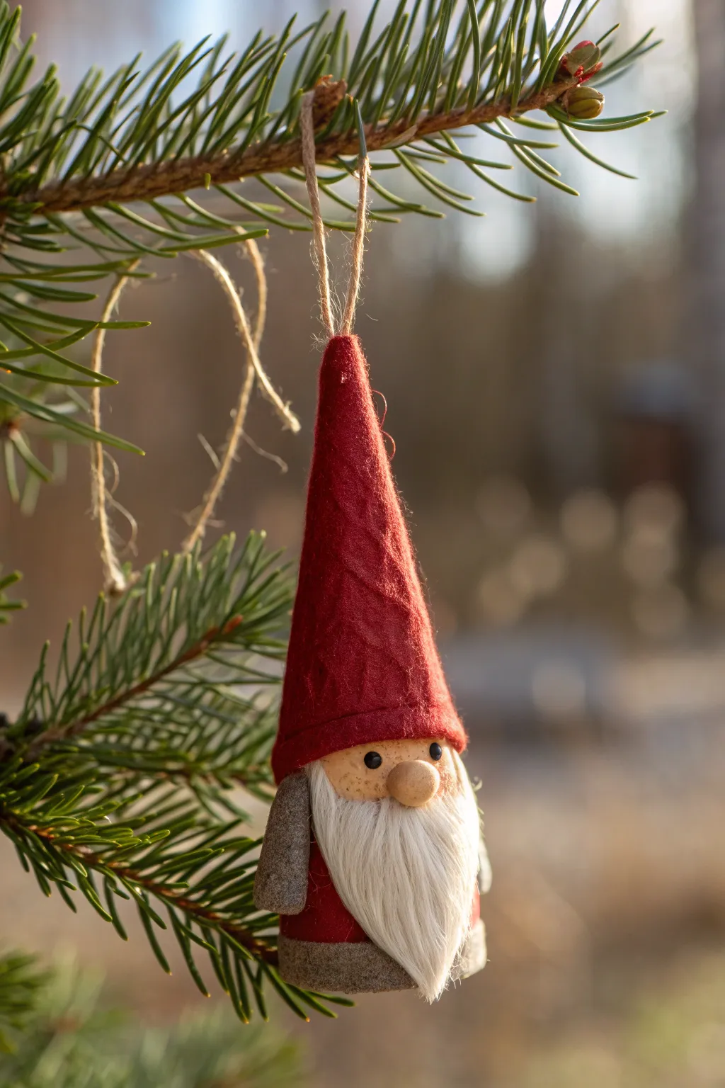 Handmade clay gnome ornament with an oversized hat, hanging on pine for cozy Christmas vibes