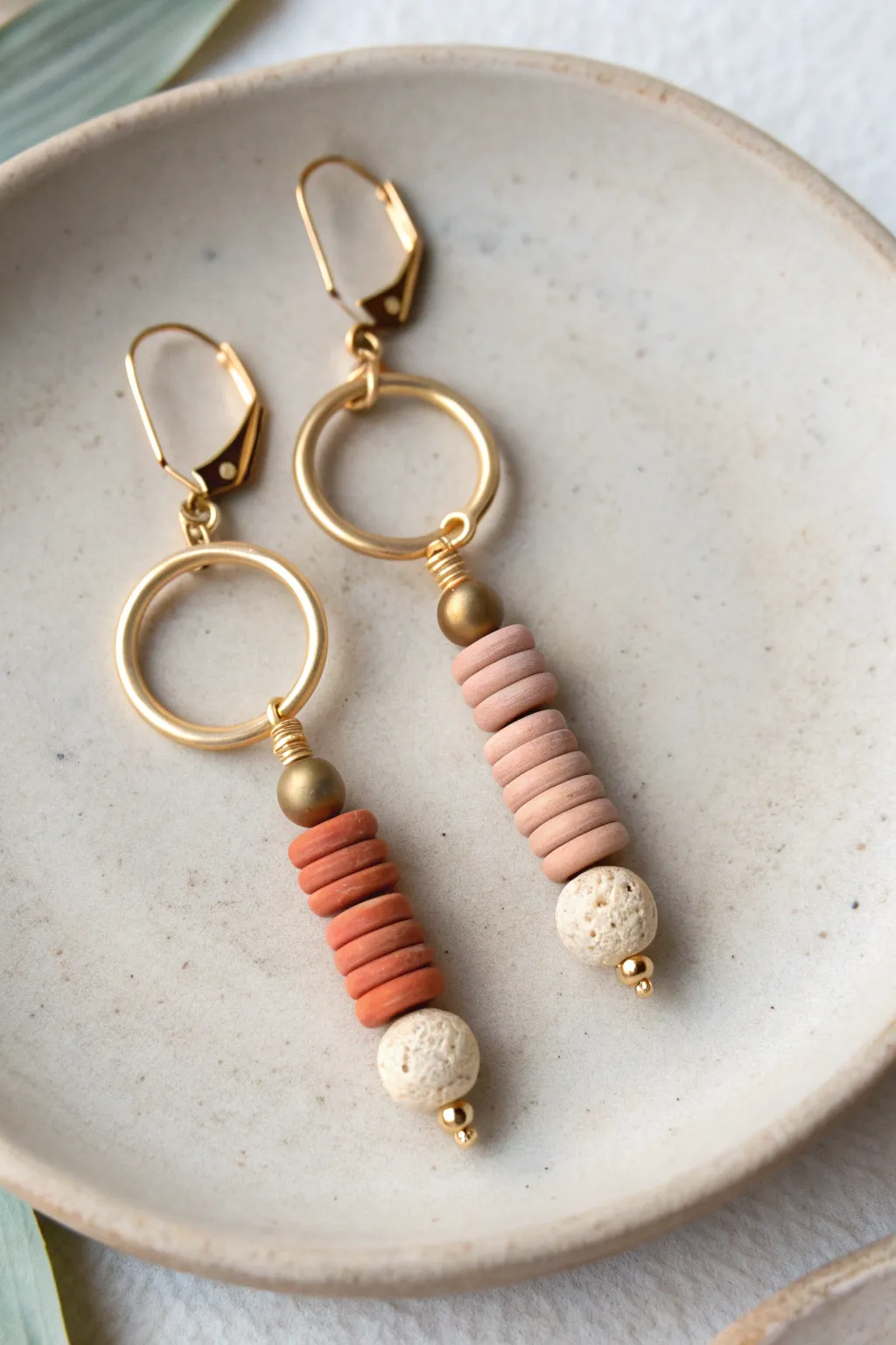 Mismatched but matching clay bead earrings in a shared earthy palette, minimalist and playful.