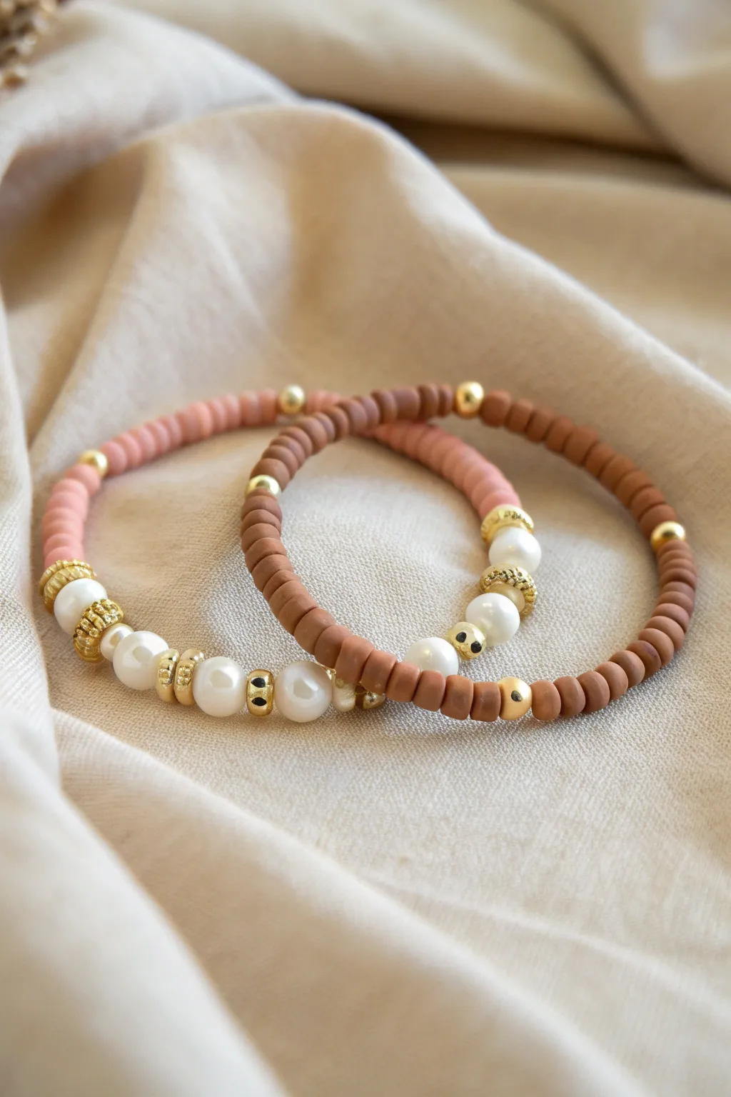 Mixed-texture bracelet stack: pastel heishi clay beads paired with pearl-style accents
