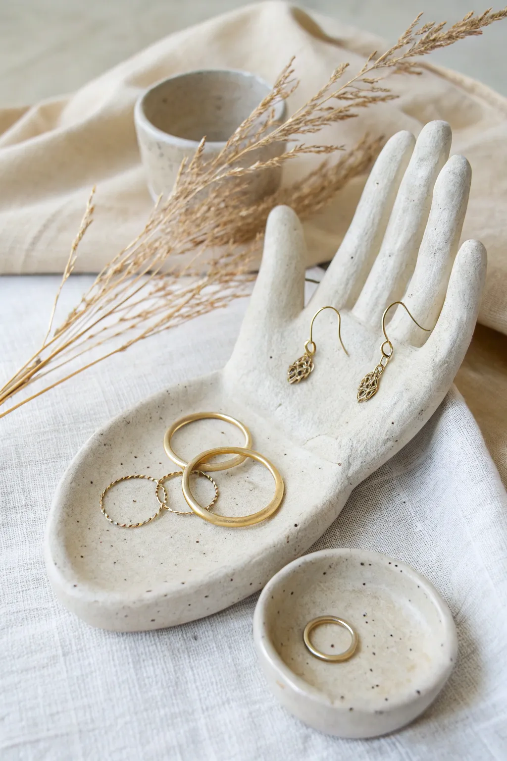 Hand-shaped clay holder with fingertip hooks keeps hoops, rings, and studs beautifully organized.