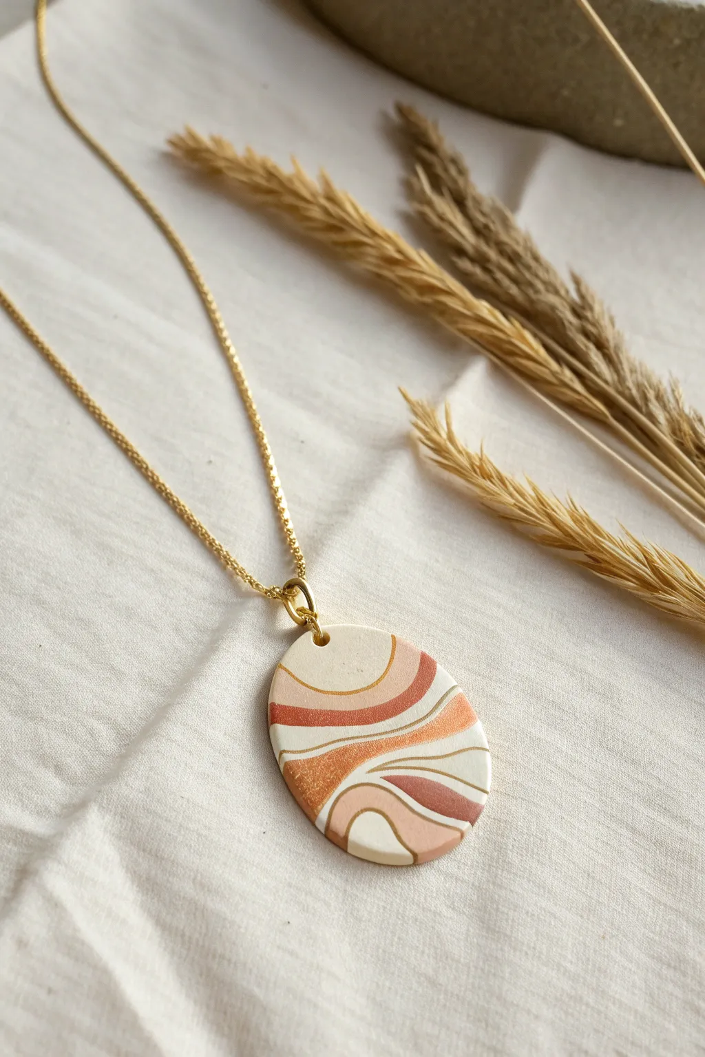 Mokume-inspired layered clay pendant on a simple chain, minimal flat lay with crisp side light