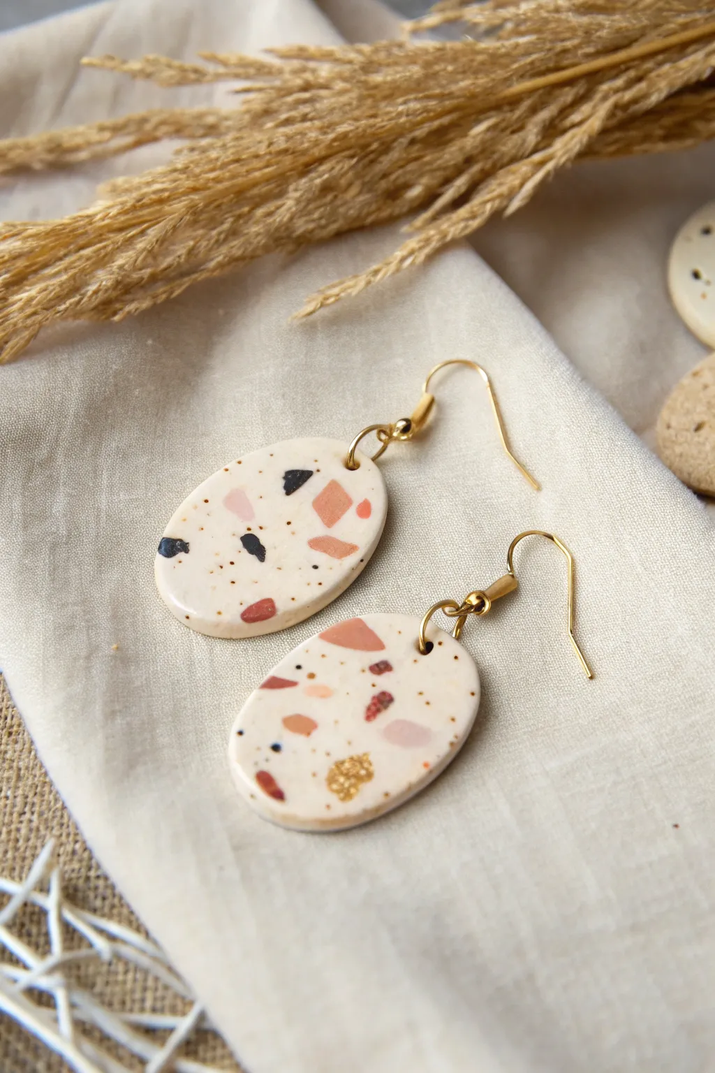 Terrazzo confetti oval dangles in warm cream with blush, tan, and black speckles.