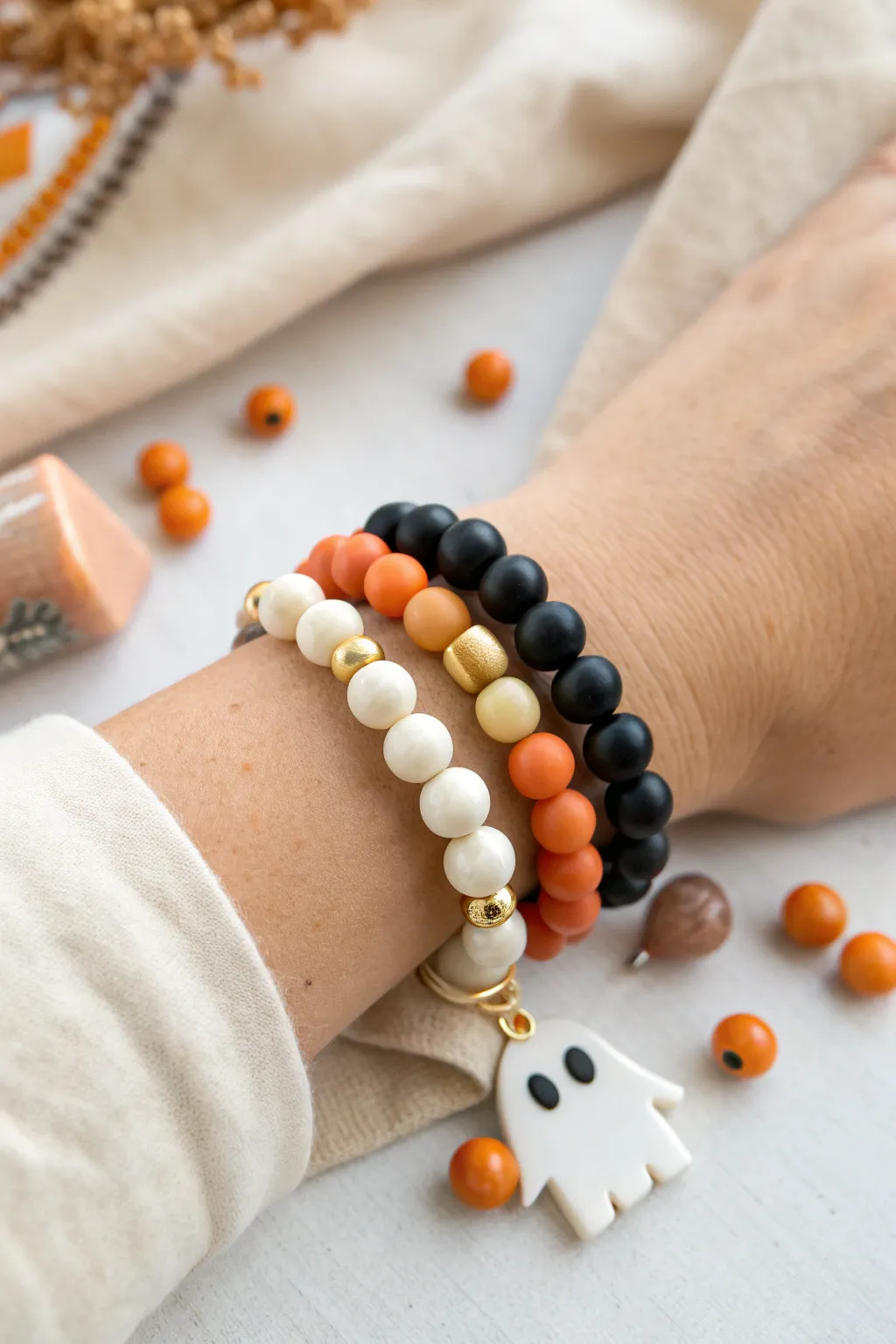 Minimalist Halloween clay bead bracelet stack in black, orange, and ivory with a cute charm accent.