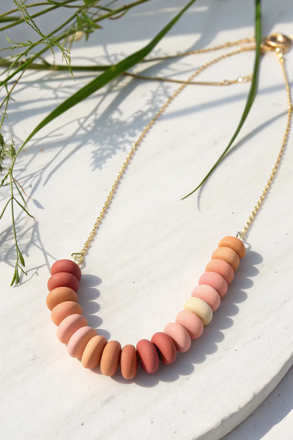 Stacked pebble ombre polymer clay necklace in blush-to-coral tones, minimal and handmade.