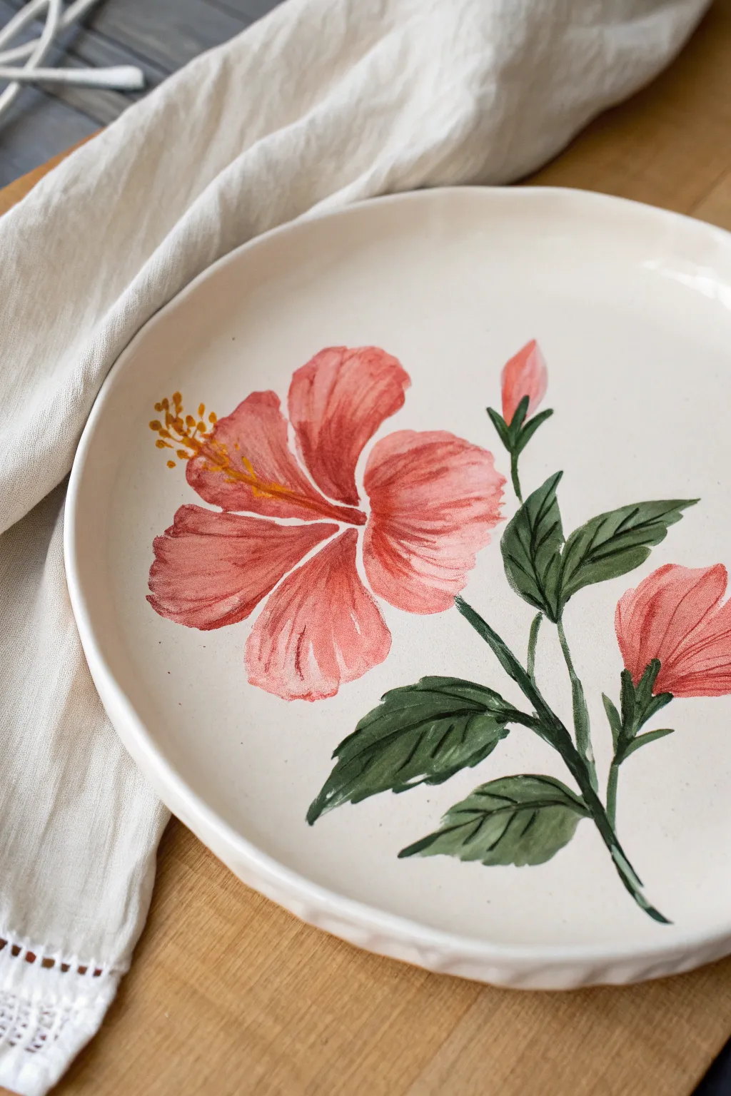Tropical hibiscus plate painting in bold coral and green, minimal yet vibrant for summer tables.