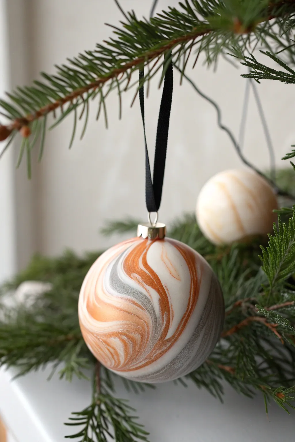 Glossy marbled clay bauble on evergreen, a simple Scandinavian boho ornament idea