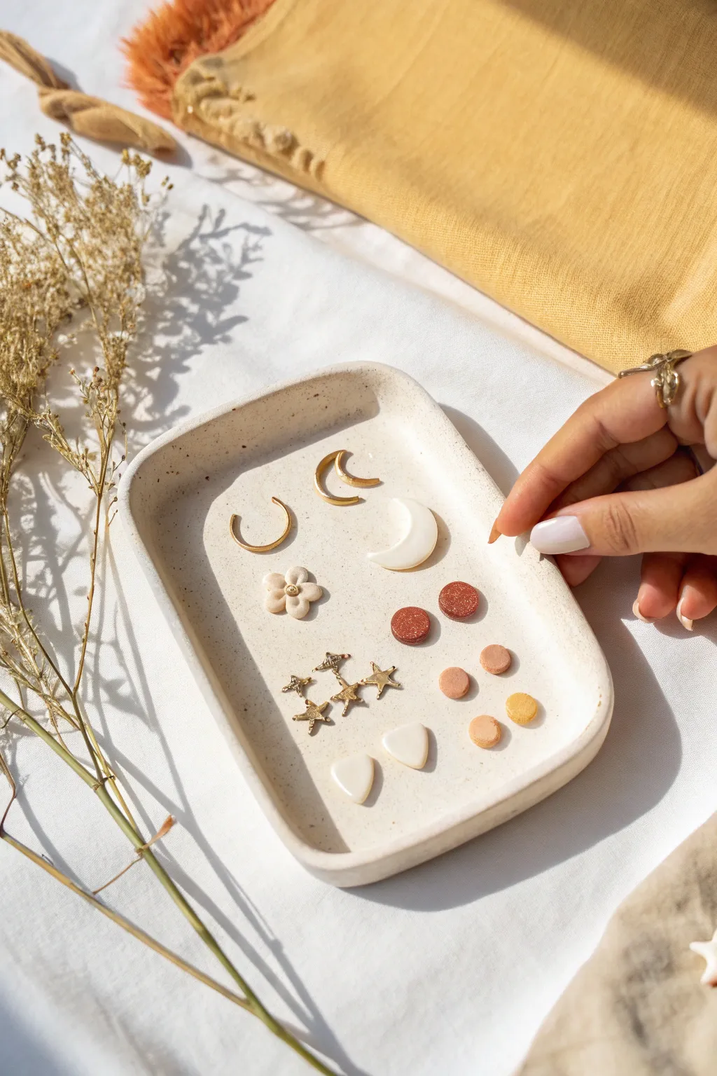 Tiny air dry clay stud and pendant shapes in boho neutrals, neatly arranged with fingertip scale.