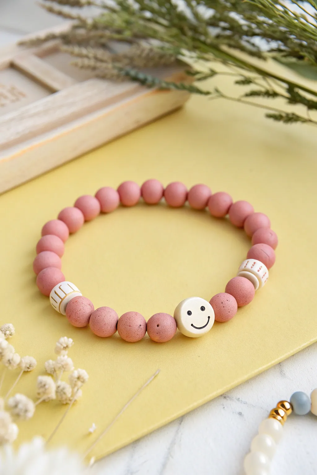 Playful pink clay bracelet with sweet smile beads on a bright, minimalist backdrop.