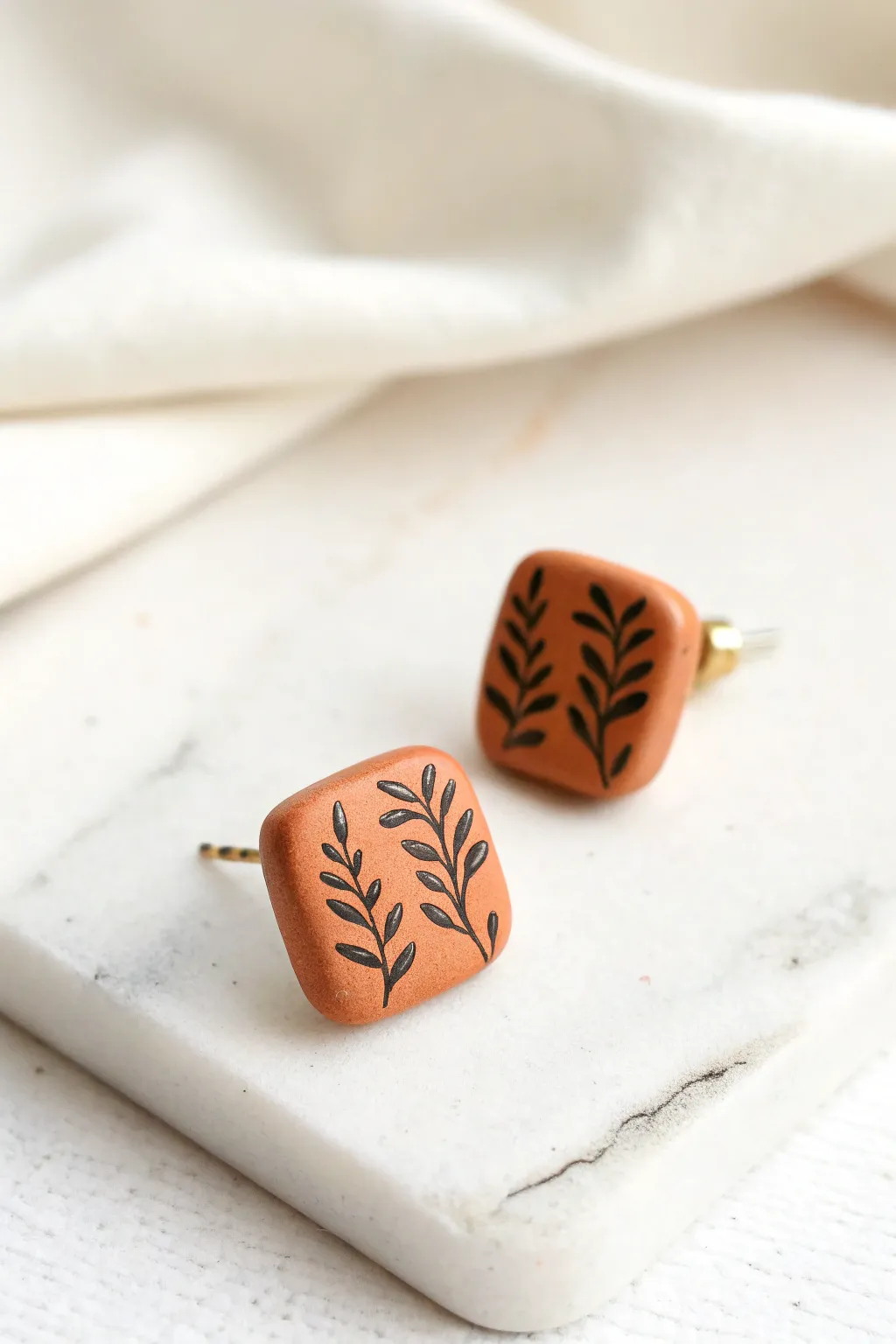 Minimal stamped line-art polymer clay studs in warm terracotta on crisp white, Pinterest-ready.