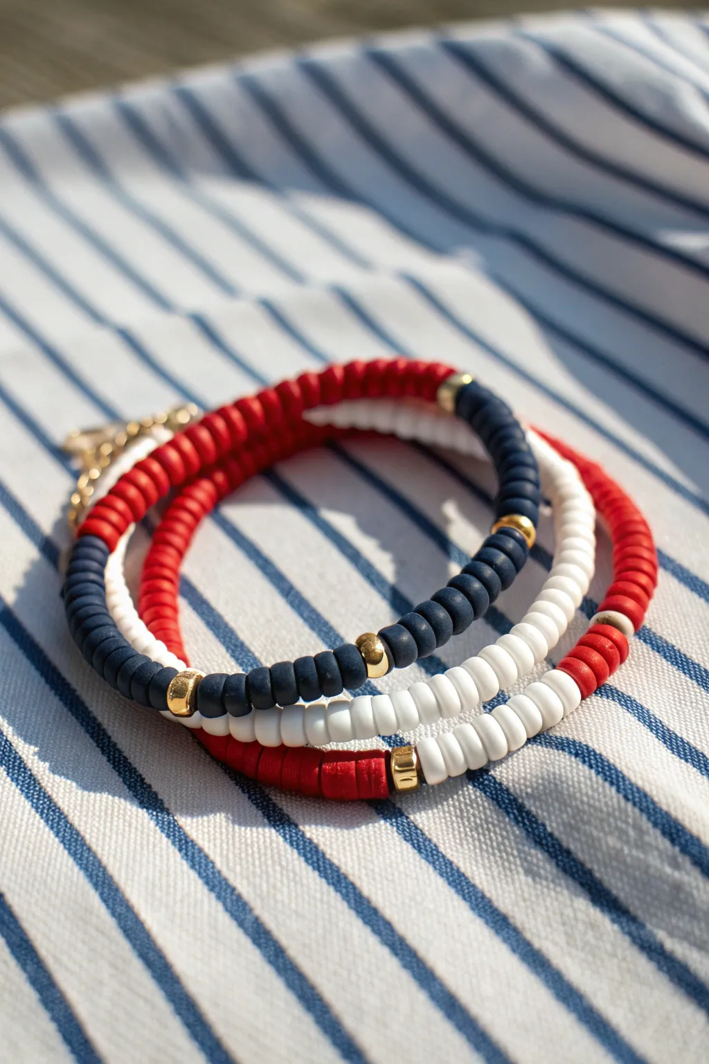 Preppy nautical clay bead bracelet in navy, red, and white with sleek gold spacers.
