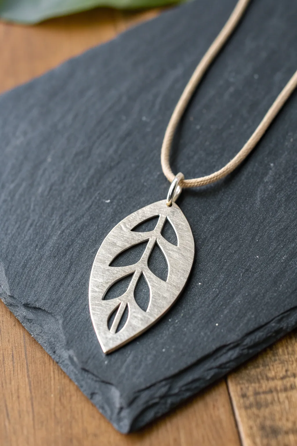 Minimal silver clay cutout pendant on dark slate, highlighting clean negative space and handmade charm.