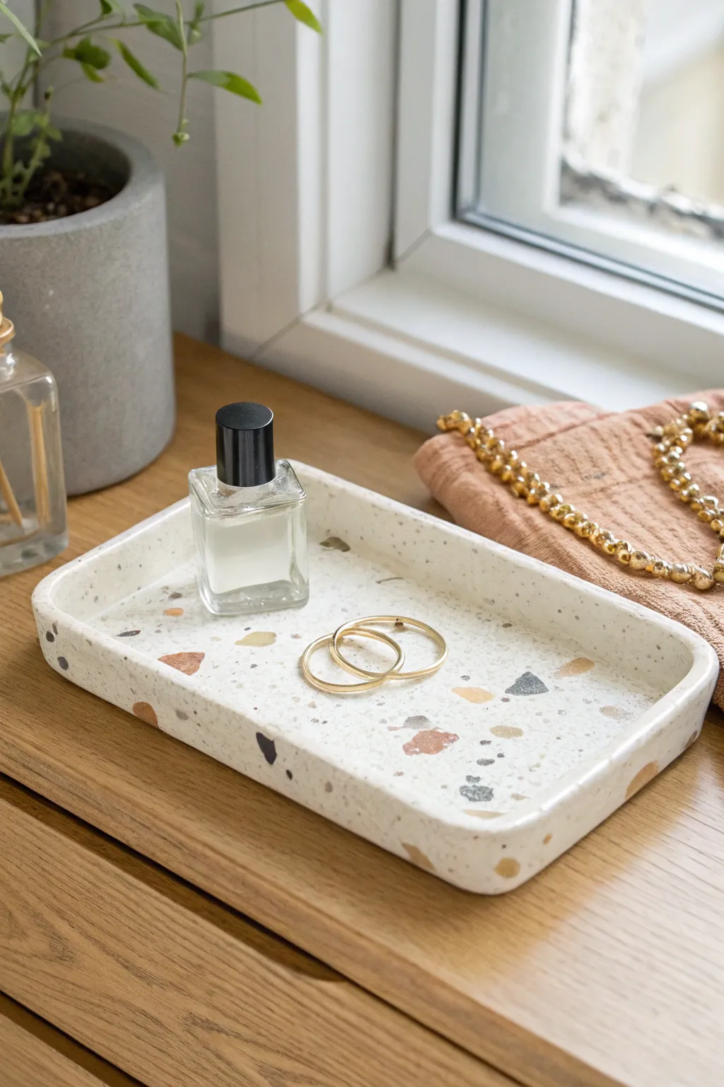 Minimal terrazzo air dry clay tray to corral perfume and jewelry on a calm, natural dresser.