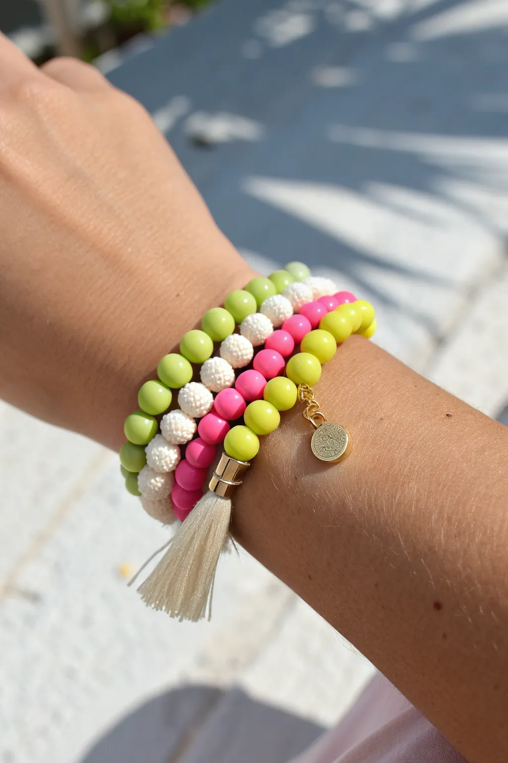 Tropical brights clay bead bracelet stack with tiny tassel, set against fresh summer greenery.